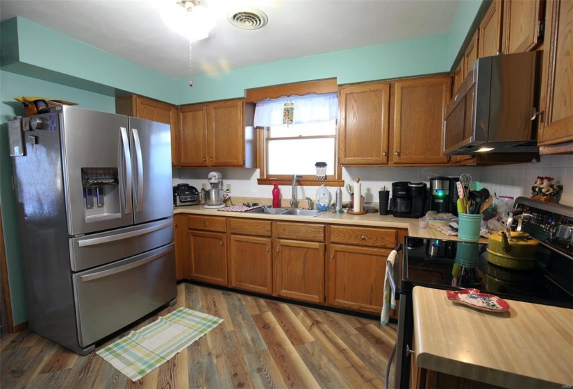 Kitchen with appliances with stainless steel finishes, backsplash, hardwood / wood-style floors, and sink