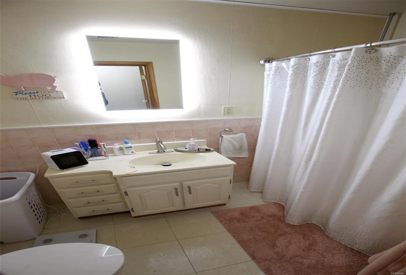 Bathroom featuring toilet, vanity, tile patterned flooring, tile walls, and curtained shower